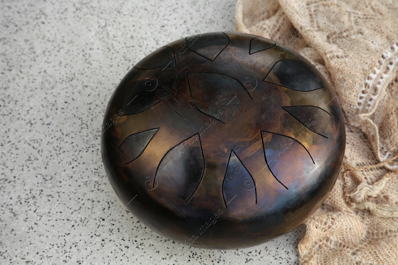 Photo of Steel tongue drum on grey table. Percussion musical instrument