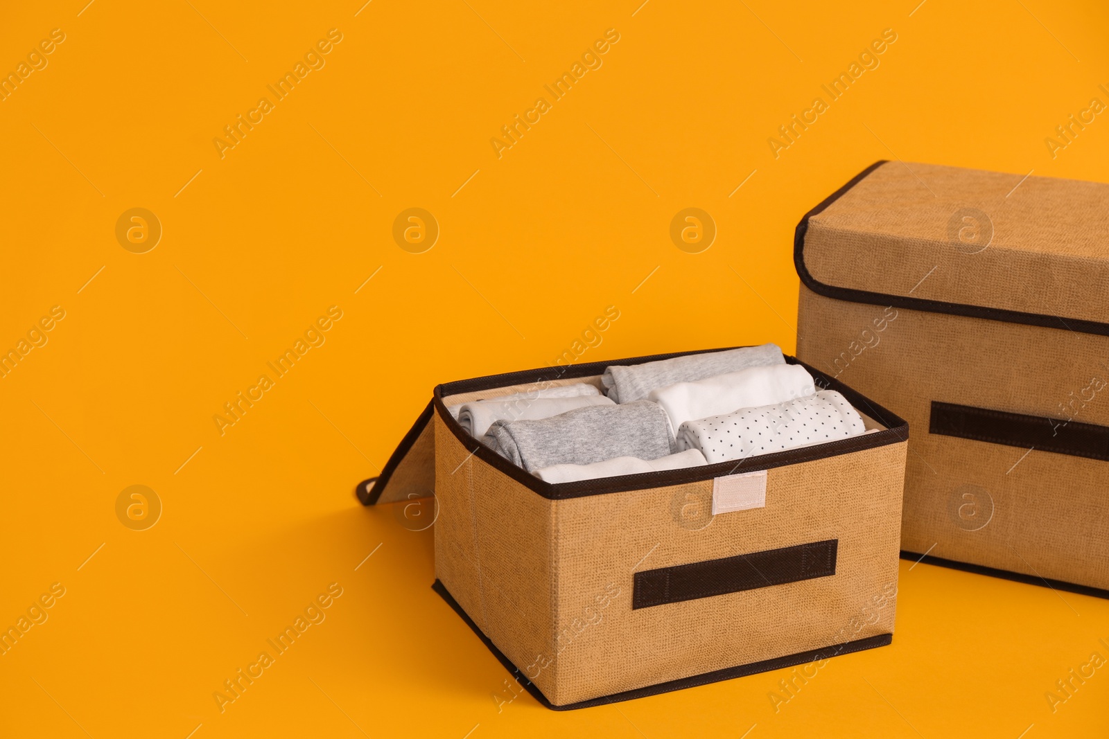 Photo of Two textile storage cases on yellow background. Space for text