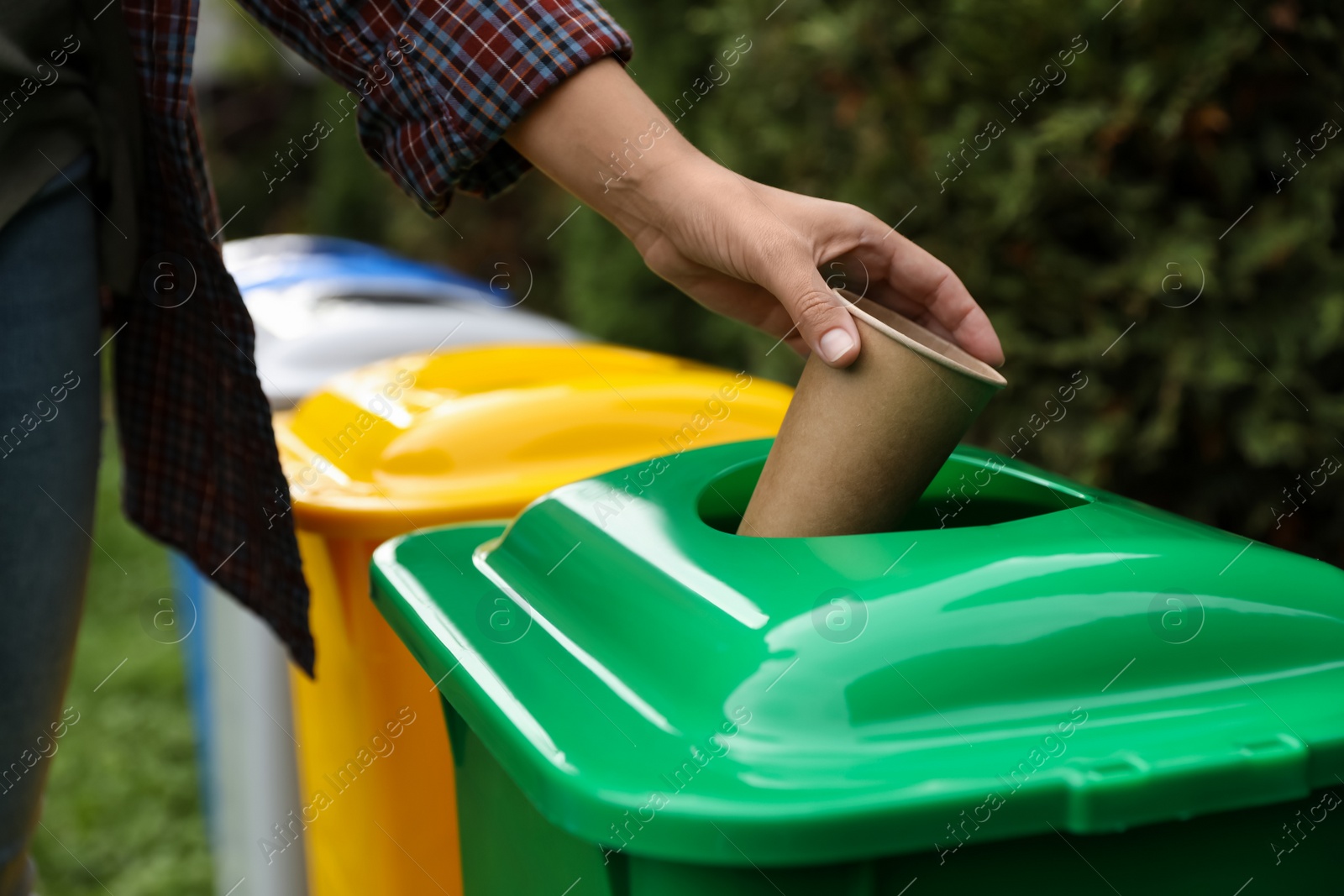 Photo of Woman throwing coffee cup into recycling bin outdoors, closeup