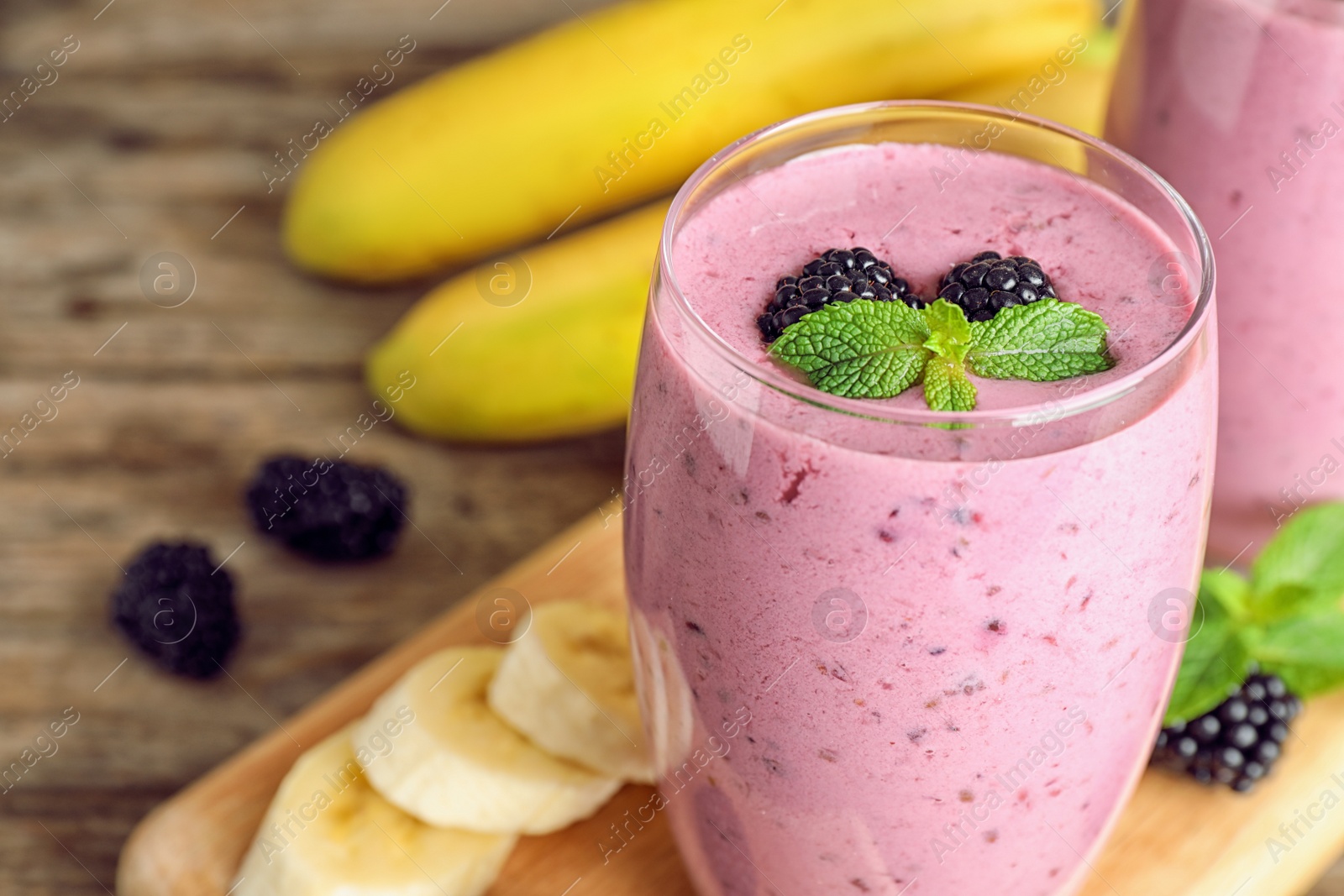 Photo of Delicious blackberry smoothie on wooden table, space for text