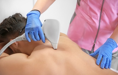 Young man undergoing laser epilation procedure in beauty salon