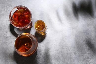 Photo of Different delicious liqueurs in glasses on grey table, flat lay. Space for text