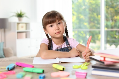 Photo of Little girl doing assignment at home. Stationery for school