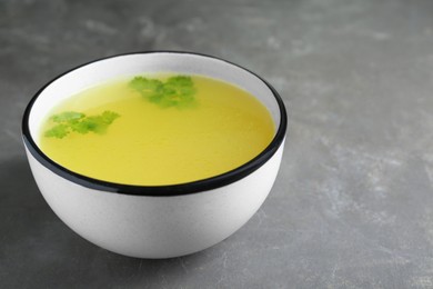 Delicious chicken bouillon with parsley on grey table. Space for text