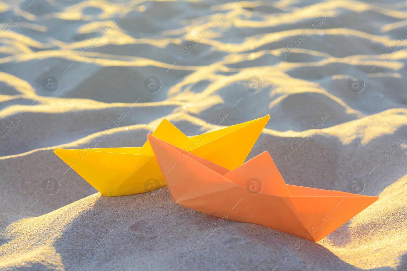 Photo of Two colorful paper boats on sand outdoors