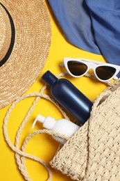 Flat lay composition with wicker bag and other beach accessories on yellow background