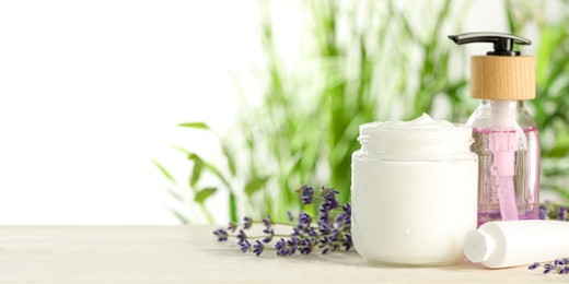 Different hand care cosmetic products and lavender flowers on white wooden table, space for text. Banner design