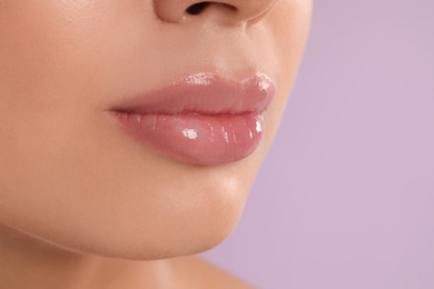 Photo of Young woman with beautiful full lips on lilac background, closeup