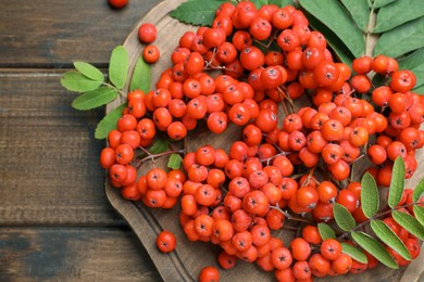 Fresh ripe rowan berries and leaves on wooden table, flat lay