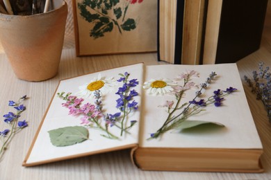 Photo of Book with beautiful dried flowers on wooden table