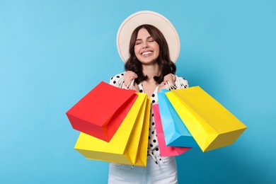 Photo of Beautiful young woman with paper shopping bags on light blue background