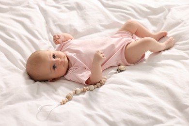 Cute little baby with toy lying on white sheets