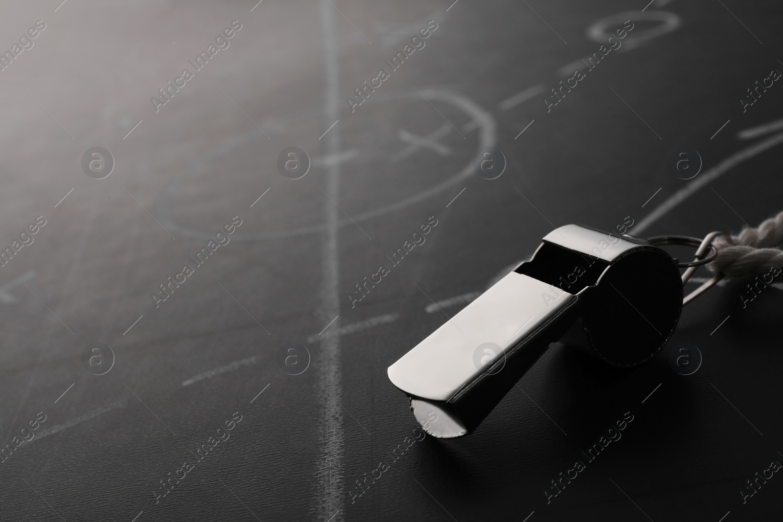 Photo of Referee whistle on chalkboard with game scheme, closeup. Space for text