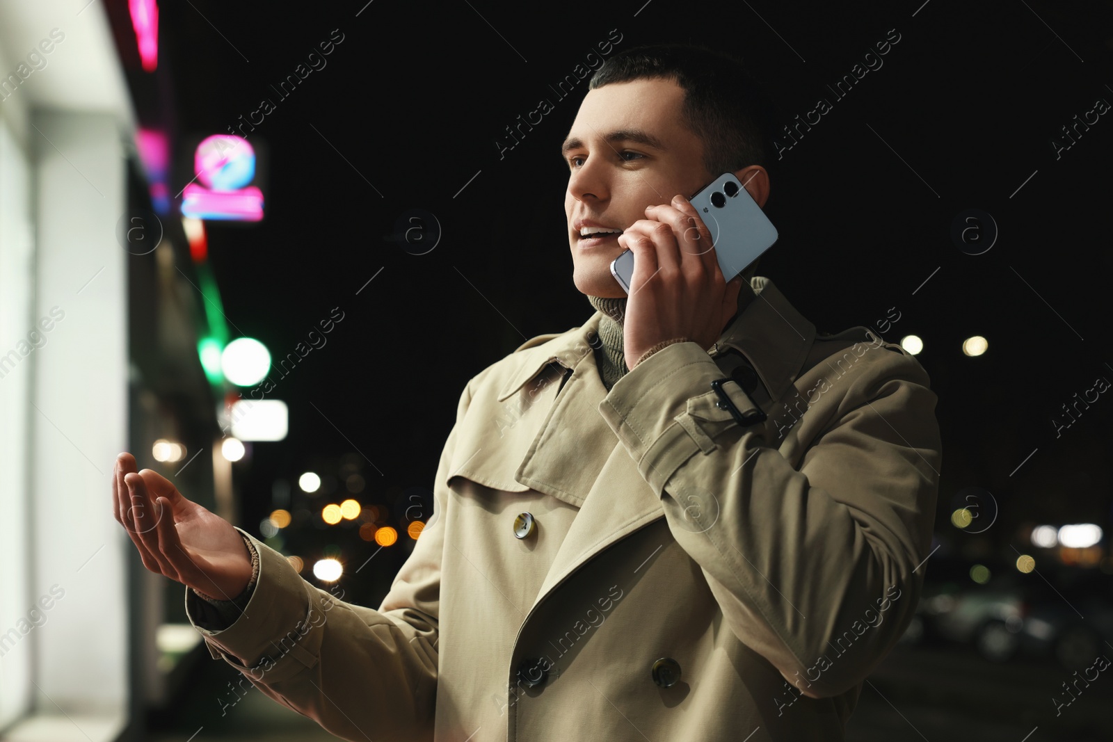 Photo of Man talking by smartphone on night city street