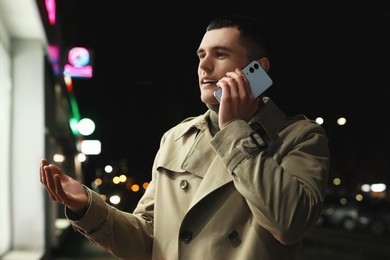 Man talking by smartphone on night city street