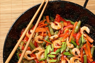 Photo of Shrimp stir fry with vegetables in wok on table, top view