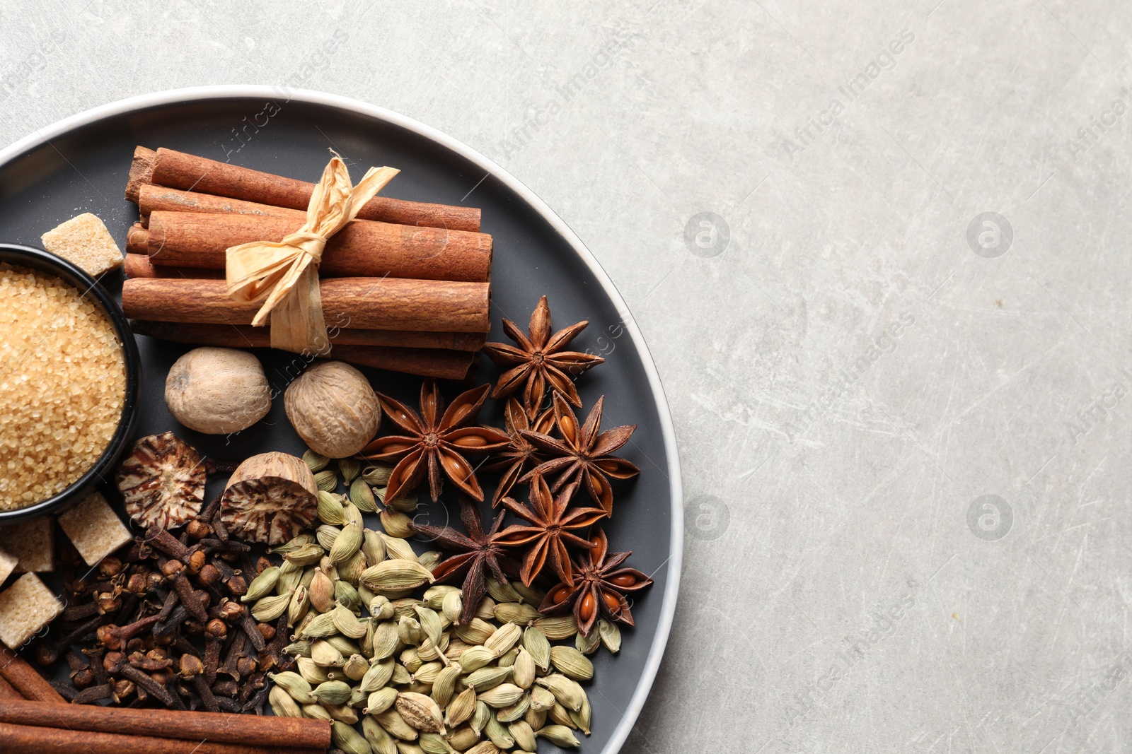 Photo of Plate with different aromatic spices on light textured table, top view. Space for text