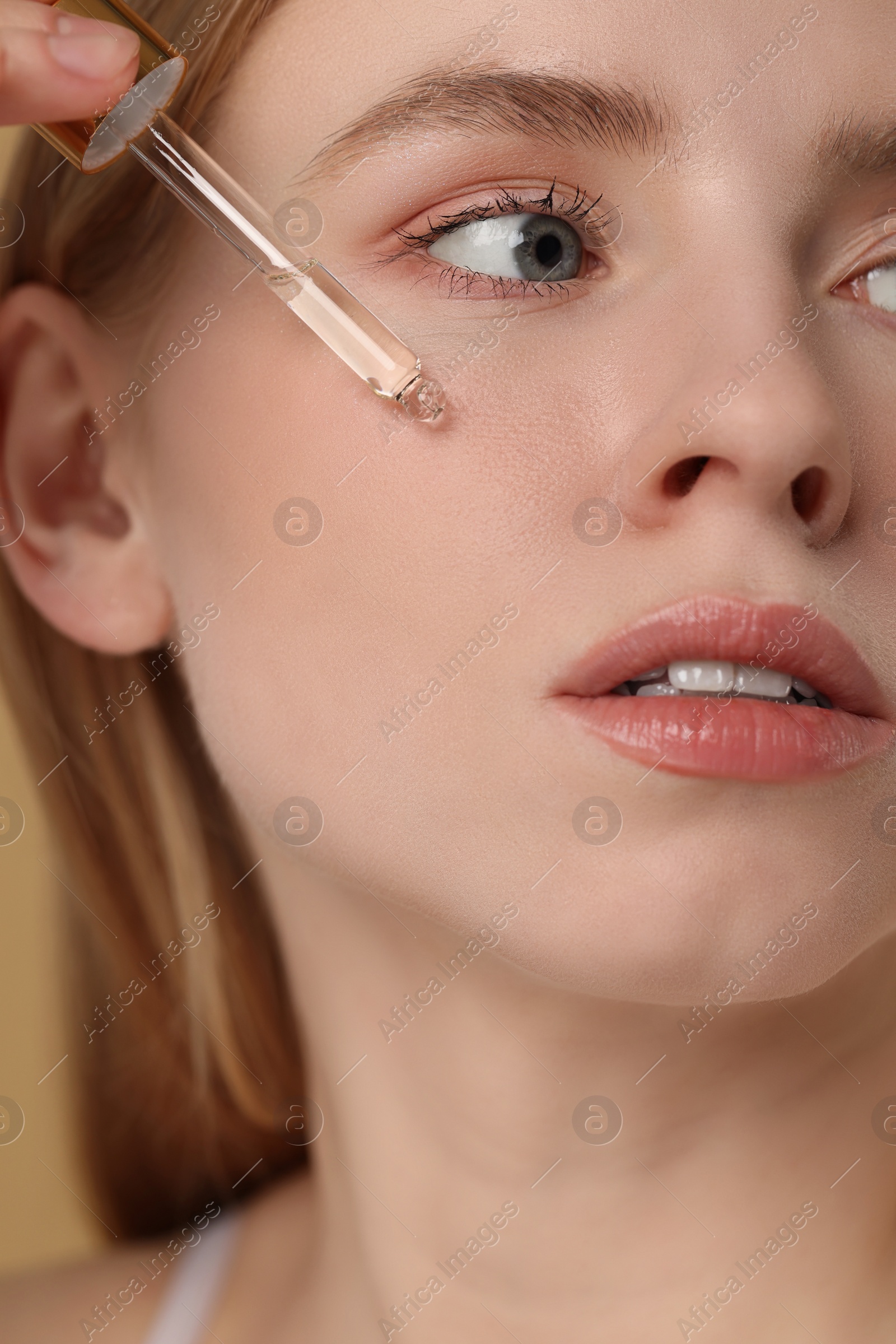 Photo of Woman applying essential oil onto face, closeup