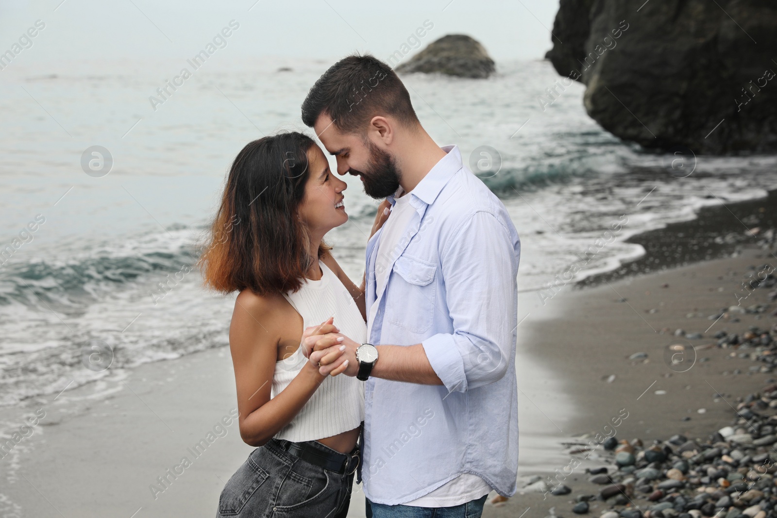 Photo of Happy young couple spending time together on beach near sea