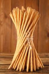 Photo of Bunch of delicious grissini sticks on wooden table