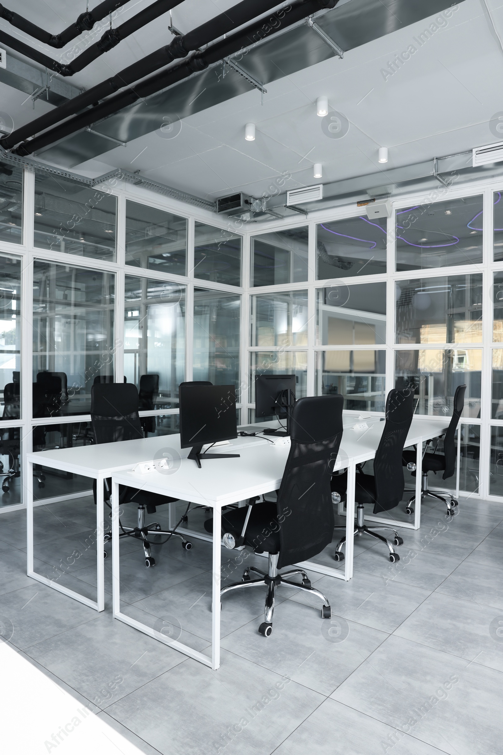 Photo of Stylish interior of open plan office. Workspace with computers, tables and chairs