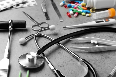 Stethoscope and different medical objects on grey table, closeup