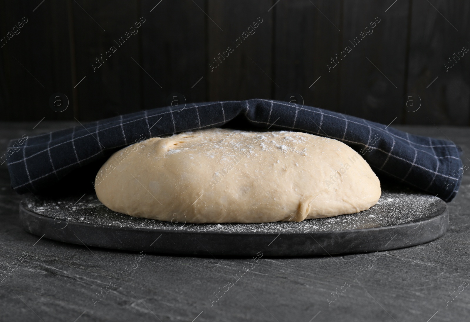 Photo of Fresh yeast dough with flour on black table