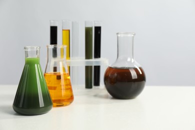 Photo of Laboratory glassware with different types of oil on white table