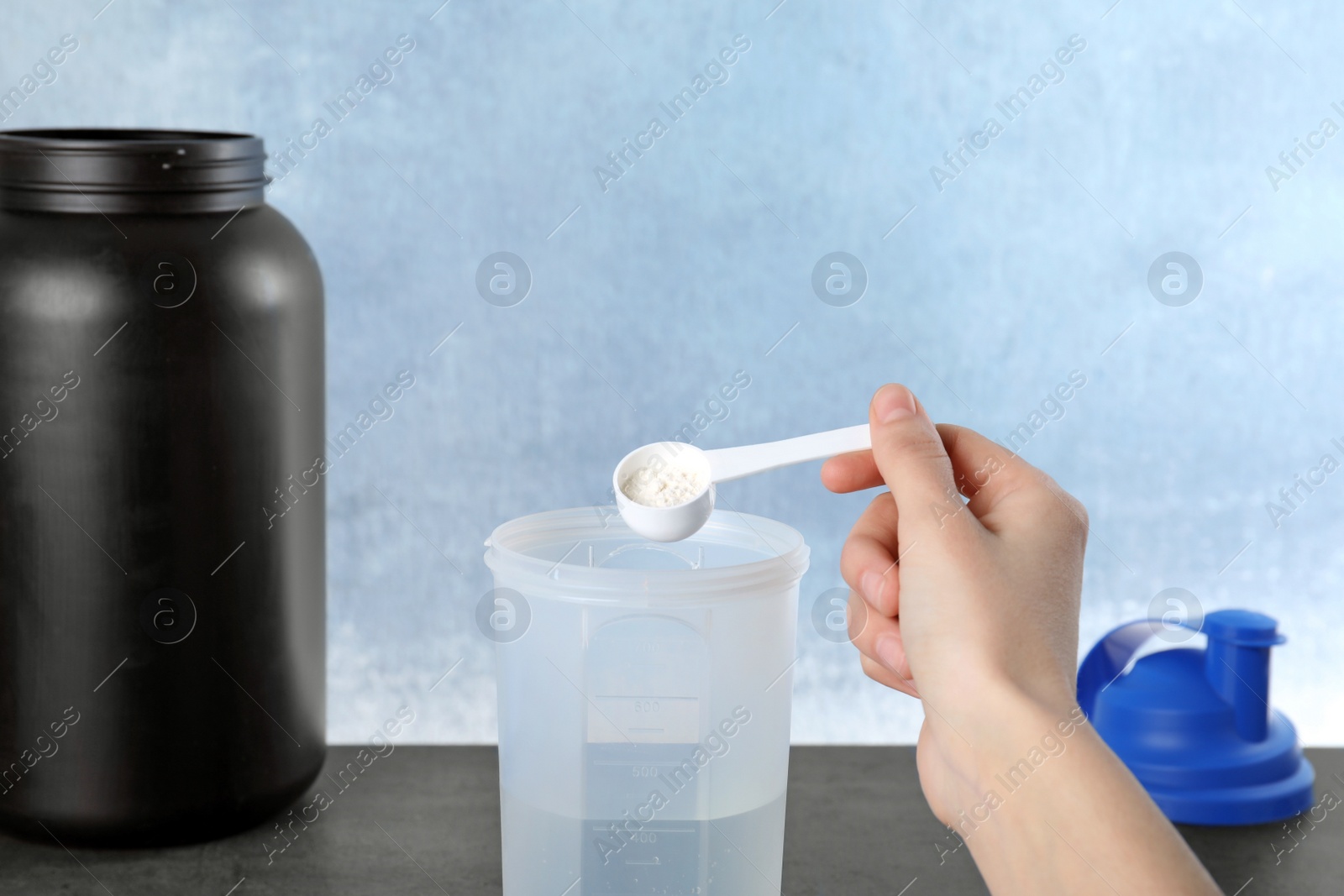 Photo of Man preparing protein shake with powder at table, closeup