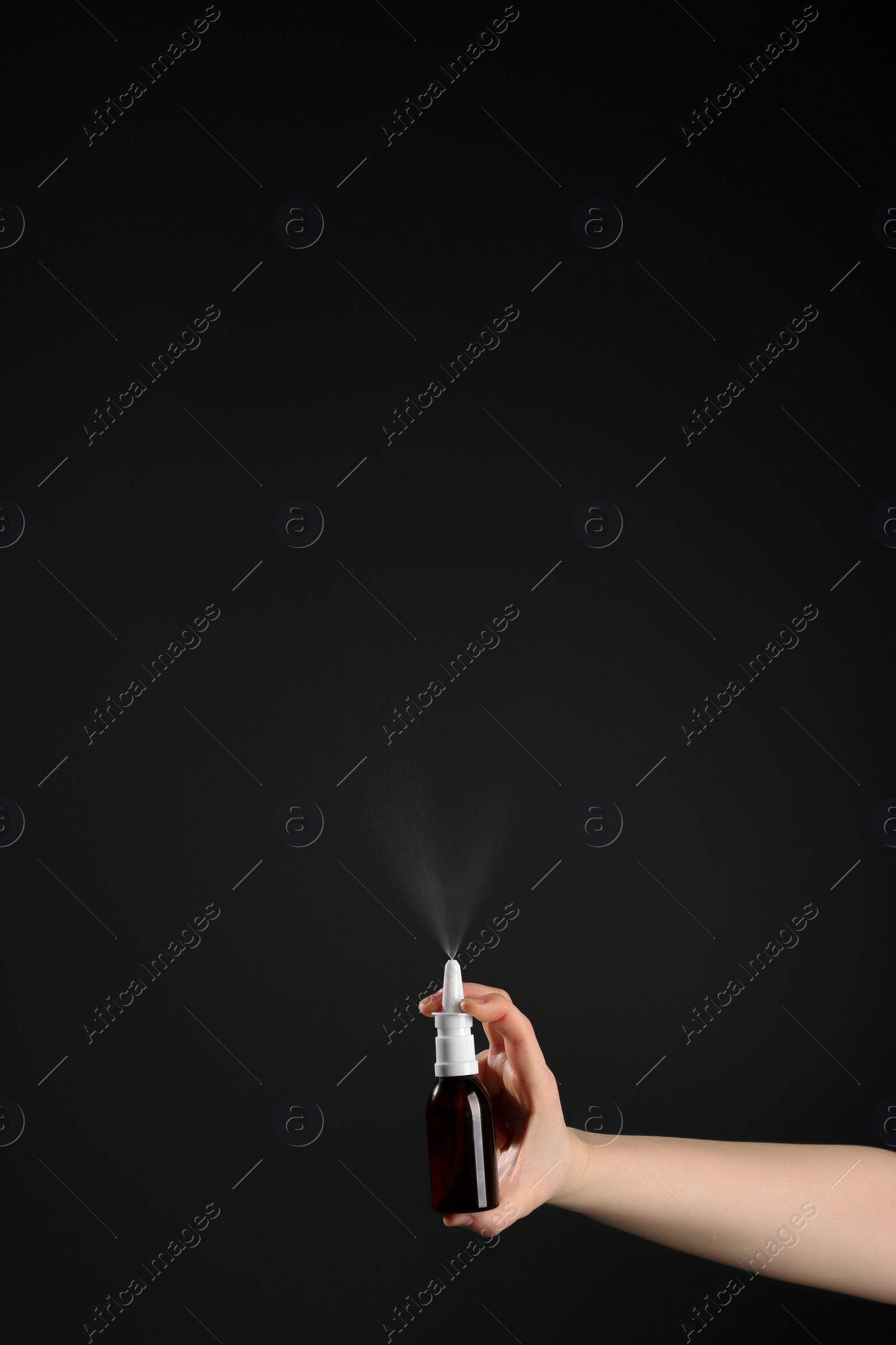 Photo of Nasal congestion. Woman spraying remedy from bottle on black background, closeup with space for text