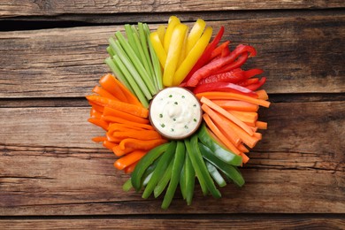 Photo of Different vegetables cut in sticks and dip sauce on wooden table, top view