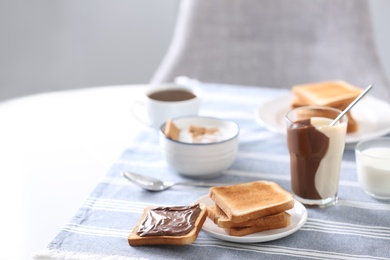 Photo of Delicious breakfast with toasts and chocolate paste on table