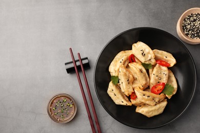 Photo of Delicious gyoza (asian dumplings) served on gray table, flat lay. Space for text