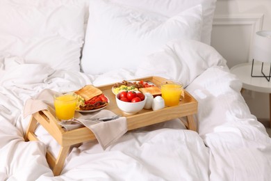 Photo of Good morning. Tray with tasty breakfast on bed at home