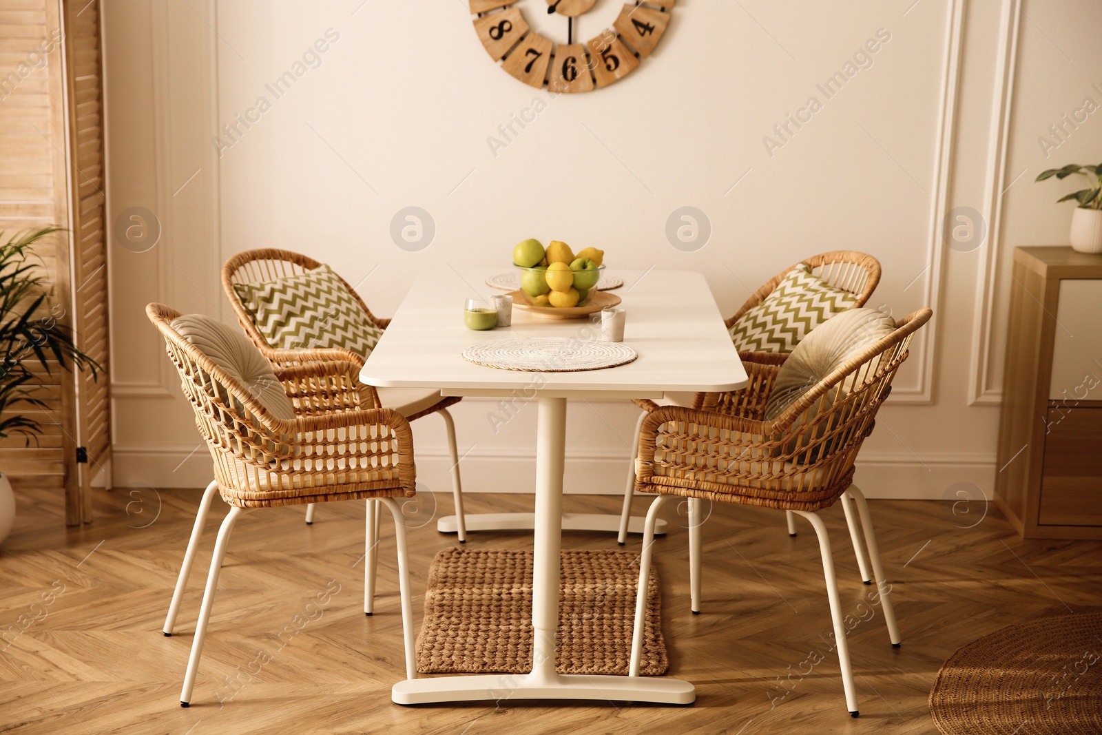 Photo of Stylish white dining table and wicker chairs in room. Interior design