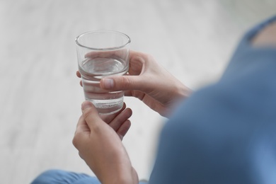 Woman holding glass of water at home, closeup