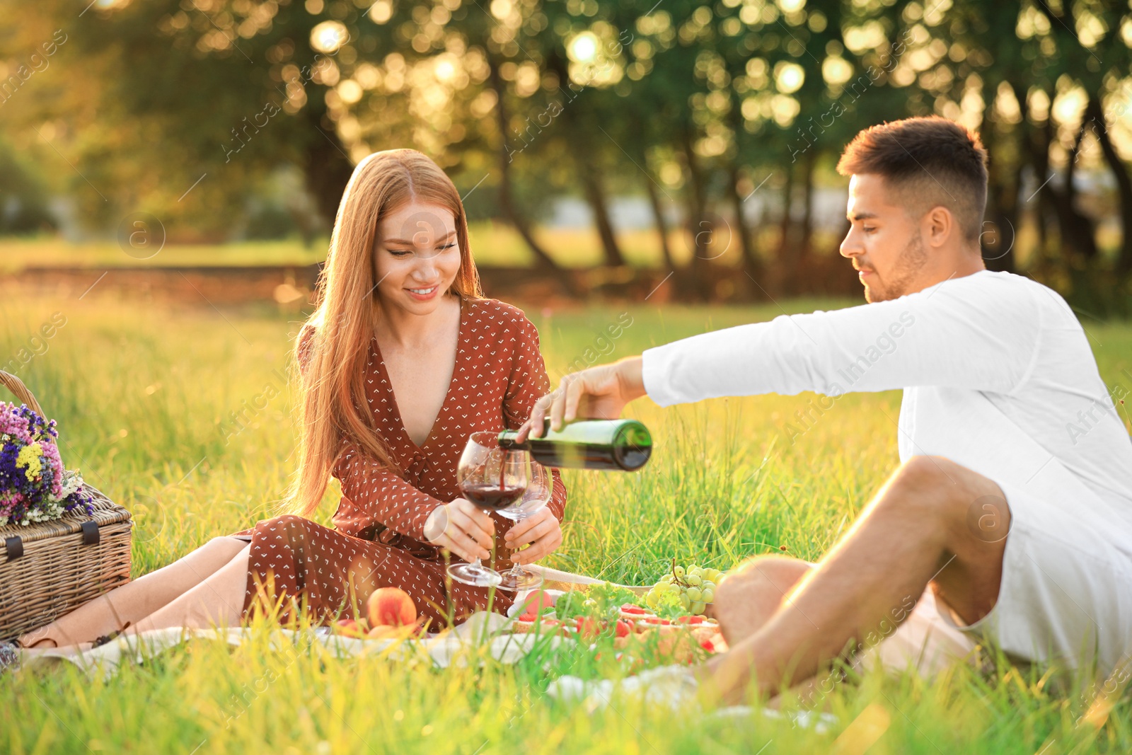 Photo of Young man and his girlfriend having picnic in green park