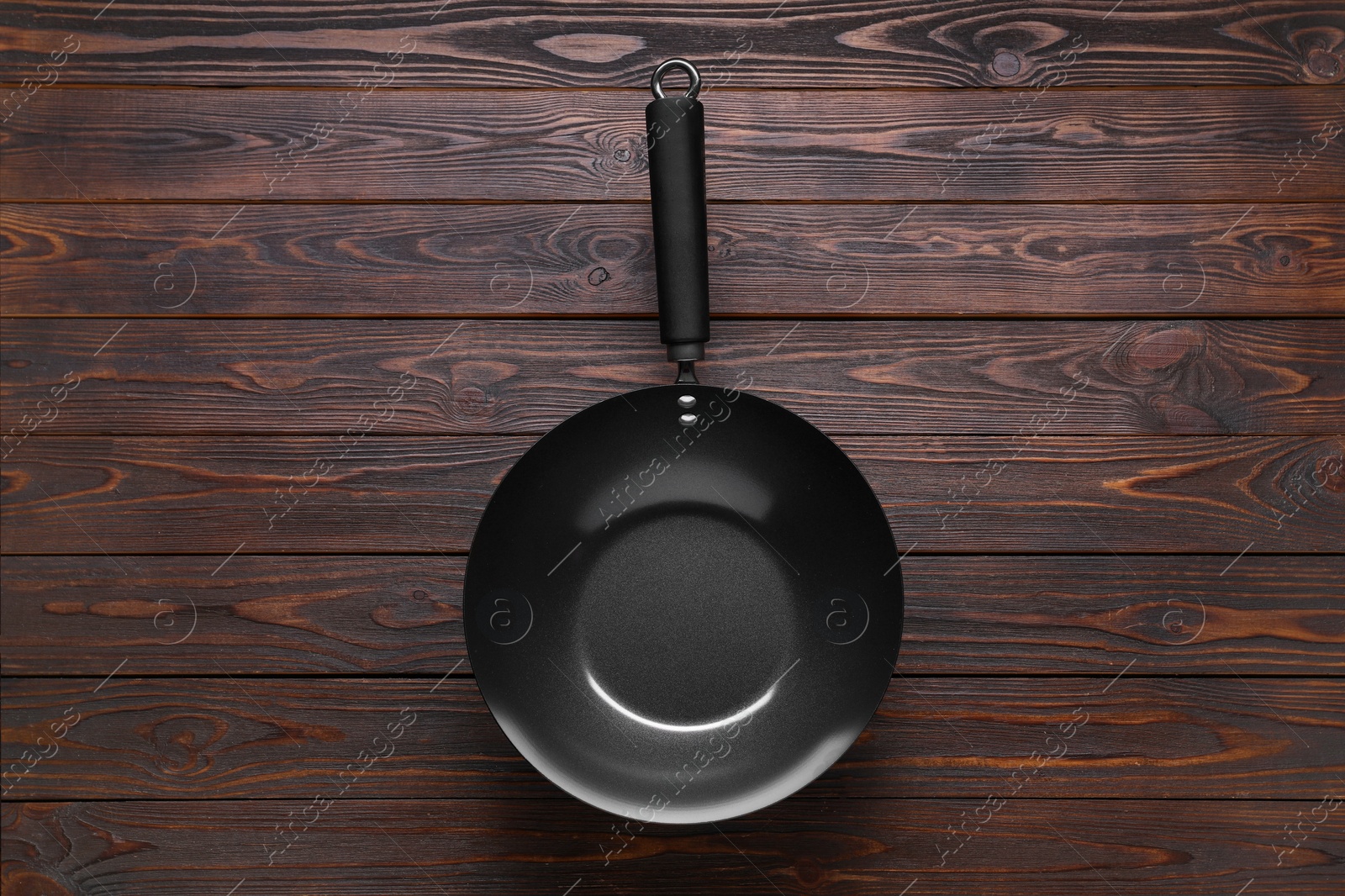 Photo of Empty iron wok on wooden table, top view. Chinese cookware