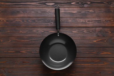 Photo of Empty iron wok on wooden table, top view. Chinese cookware