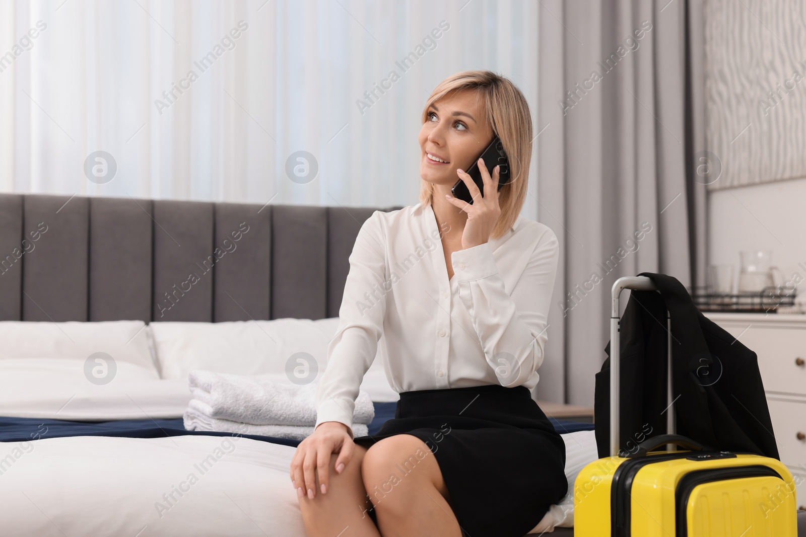 Photo of Smiling businesswoman talking on smartphone in stylish hotel room