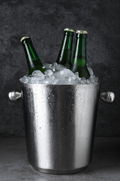 Photo of Metal bucket with beer and ice cubes on grey table