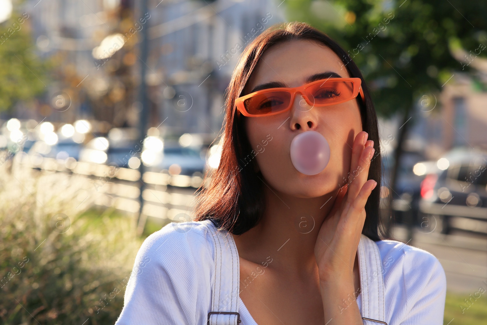 Photo of Beautiful woman in sunglasses blowing gum outdoors