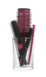 Photo of Set of professional hair brushes and combs in glass holder isolated on white