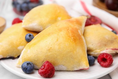 Photo of Delicious samosas with berries on white marble table, closeup