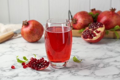 Photo of Tasty pomegranate juice in glass and fresh fruits on white marble table