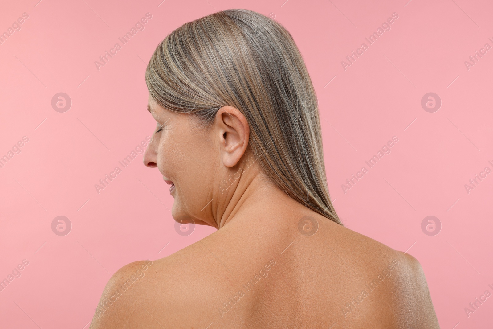 Photo of Beautiful woman with healthy skin on pink background, back view