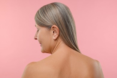 Photo of Beautiful woman with healthy skin on pink background, back view