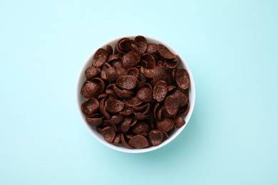 Photo of Breakfast cereal. Chocolate corn flakes in bowl on light blue table, top view