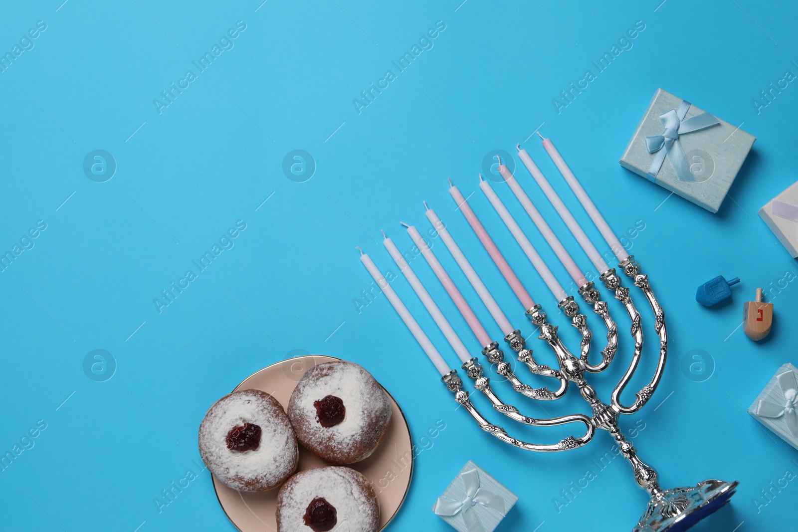 Photo of Flat lay composition with Hanukkah menorah and donuts on light blue background, space for text