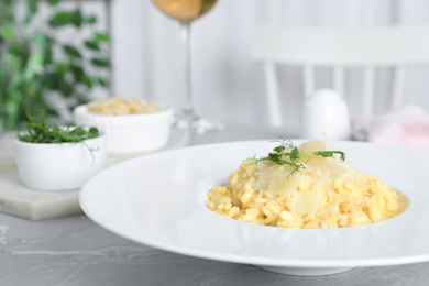 Photo of Delicious risotto with cheese on grey marble table indoors